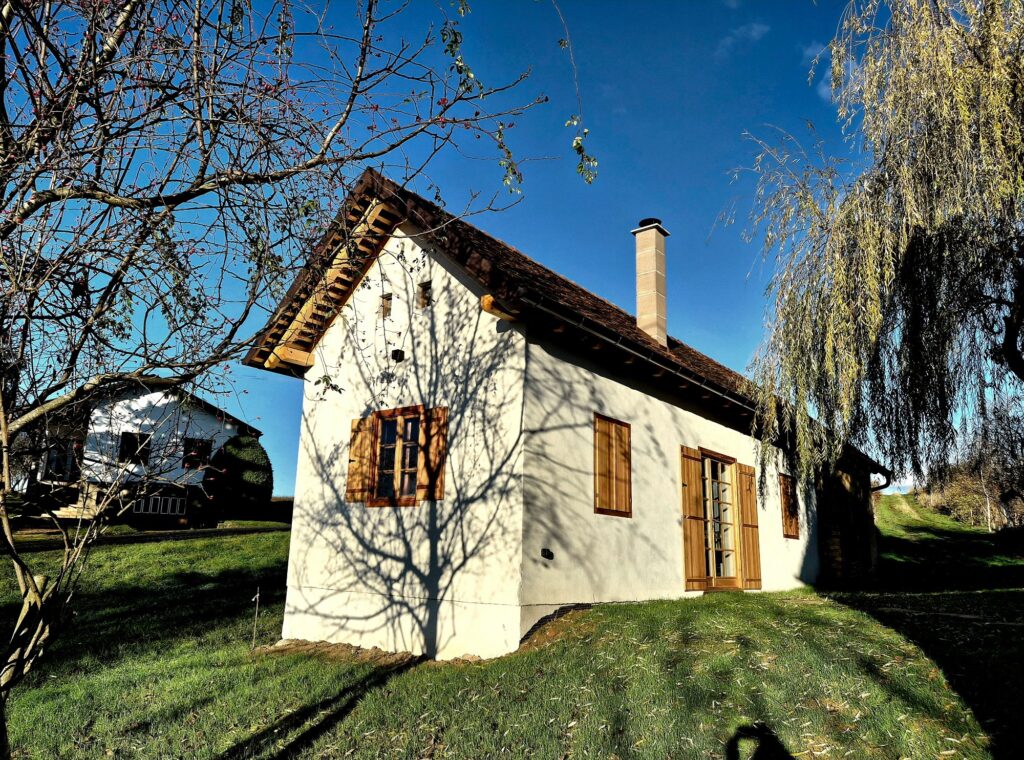 Revitalisiertes Kellerstöckl im Südburgenland mit weißer Fassade, Holzfensterläden und neuem Kamin